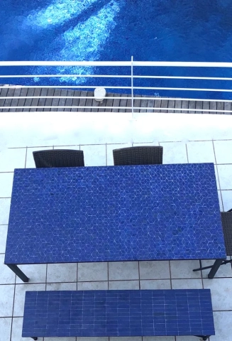 Grande table pour 6 personnes en zellige bleu Roi sur terrasse en bord de piscine et banc en zellige et fer forgé