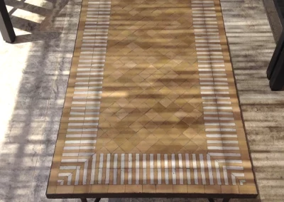 Longue table basse en zellige sous pergola, motif rayé bicolore ocre cuivré et blanc