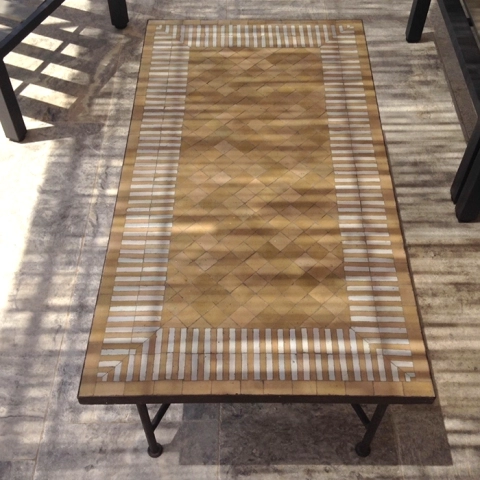 Longue table basse en zellige sous pergola, motif rayé bicolore ocre cuivré et blanc