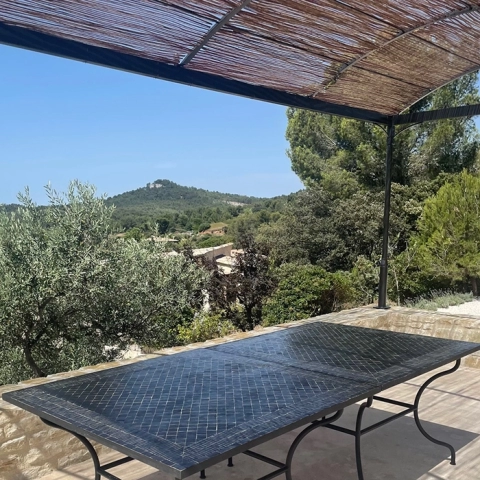 Grandes tables en zellige sur une terrasse du sud de la France. Couleur noire et motif rayé, pieds en fer forgé