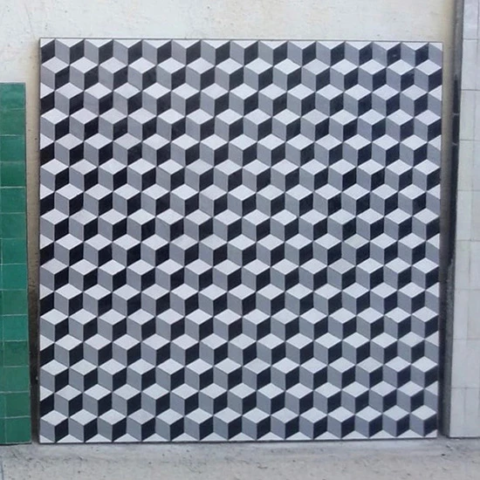 Visuel très moderne sur un grand plateau de table carrée en zellige gris, blanc et noir.