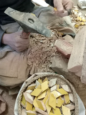 Artisan sur la finition de zellige en forme de losange jaune pour la création d'un motif cube en zellige